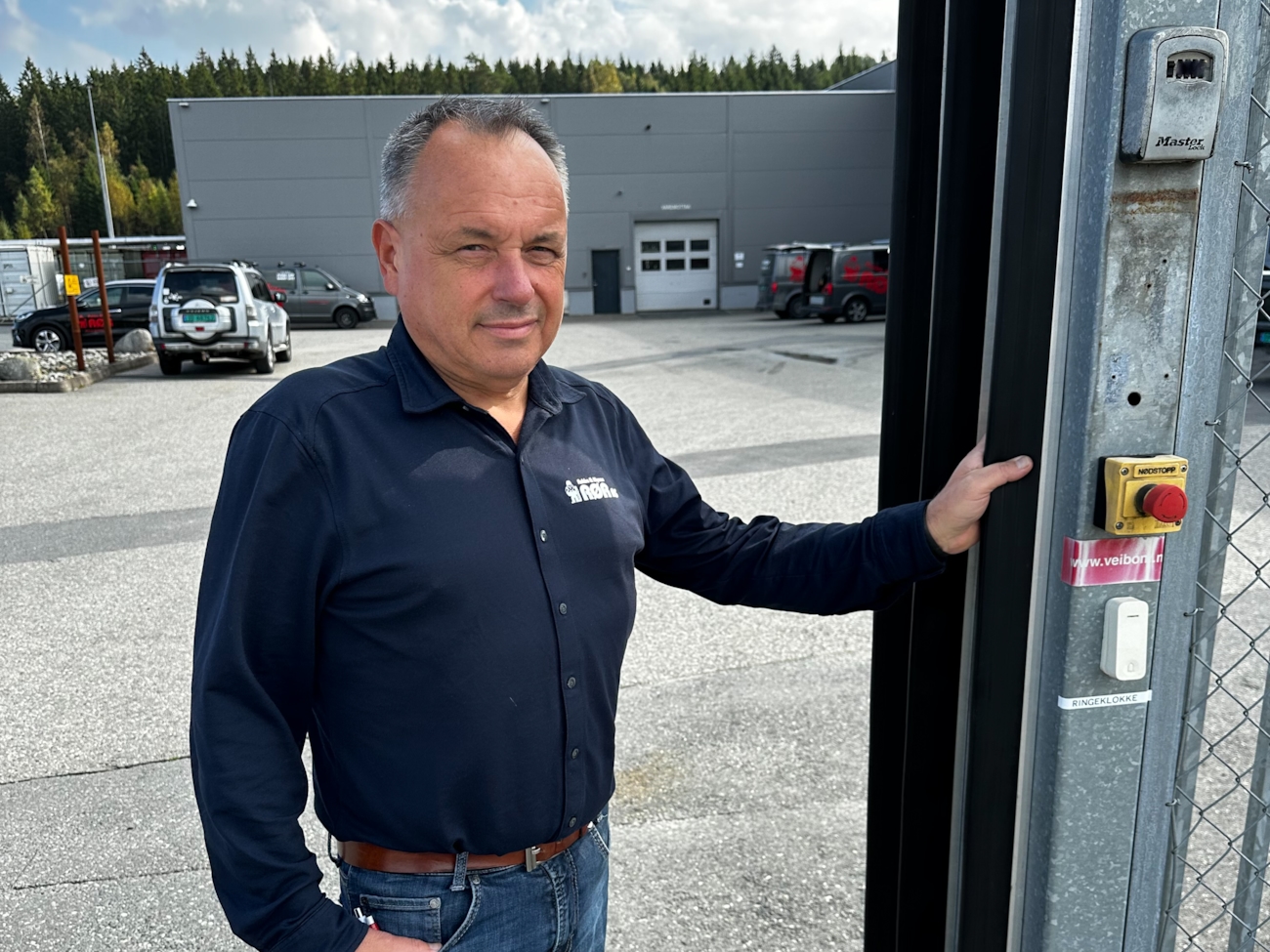 Daglig leder Tollef Berger i Askim & Mysen Rør, foran porten som gjerder inn hele arbeidsplassen. 