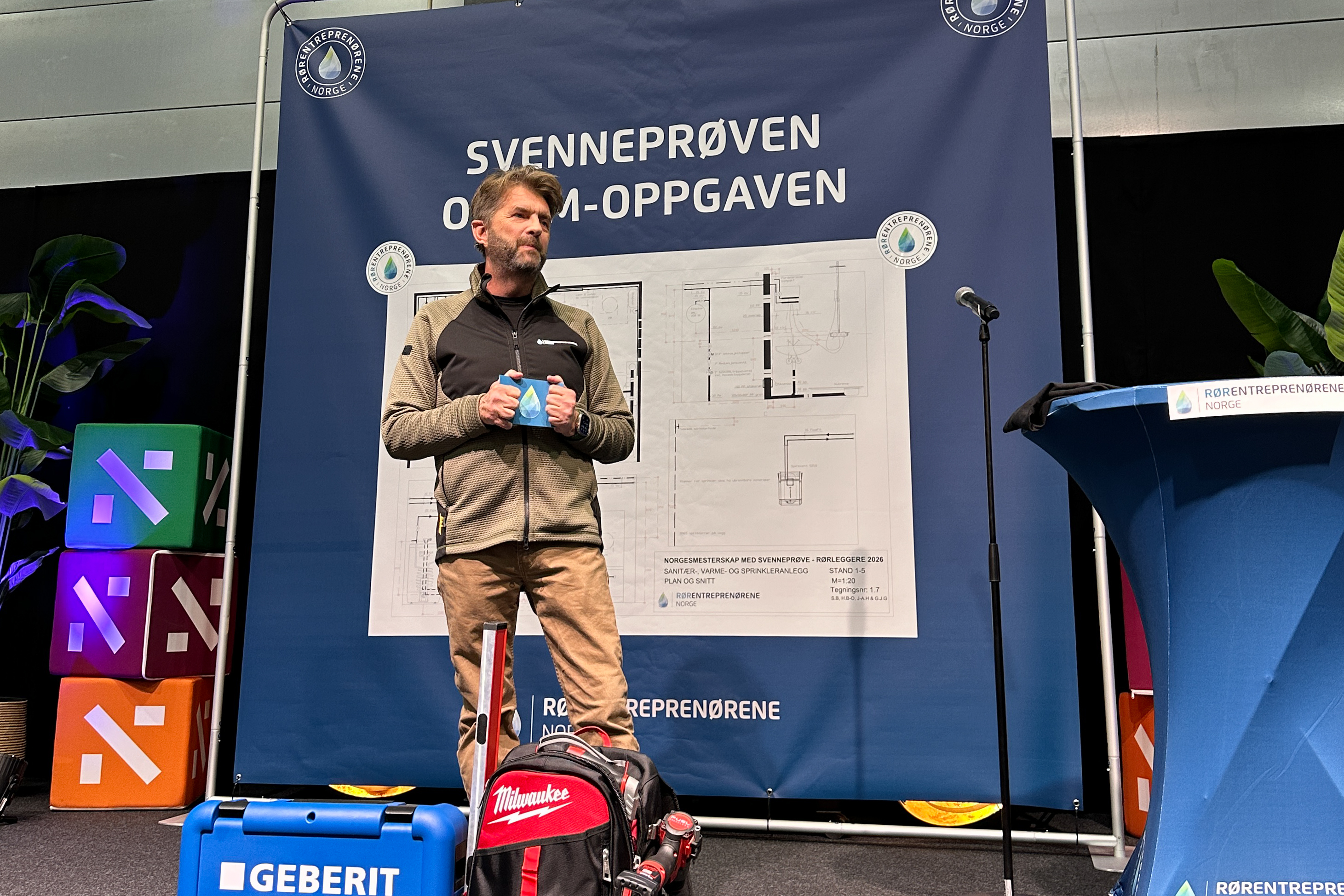 Bildet viser Are Skaar Nielsen, fagsjef i R&oslash;rNorge, og prosjektleder for R&oslash;rlegger-NM som st&aring;r p&aring; en scene og prater
