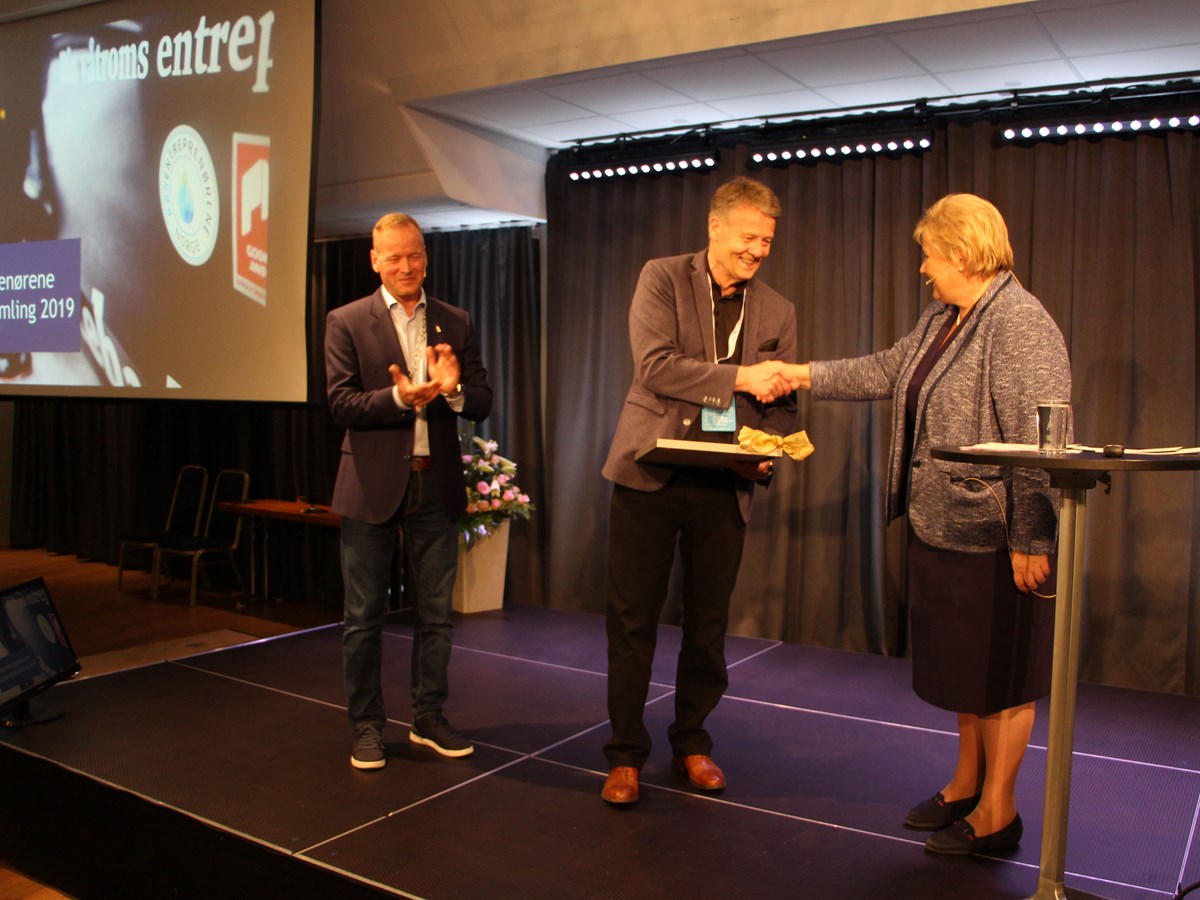 Tor Backe mottar diplom og medalje av statsminister Erna Solberg, mens styreleder Torkild Korsnes i Rørentreprenørene Norge applauderer.