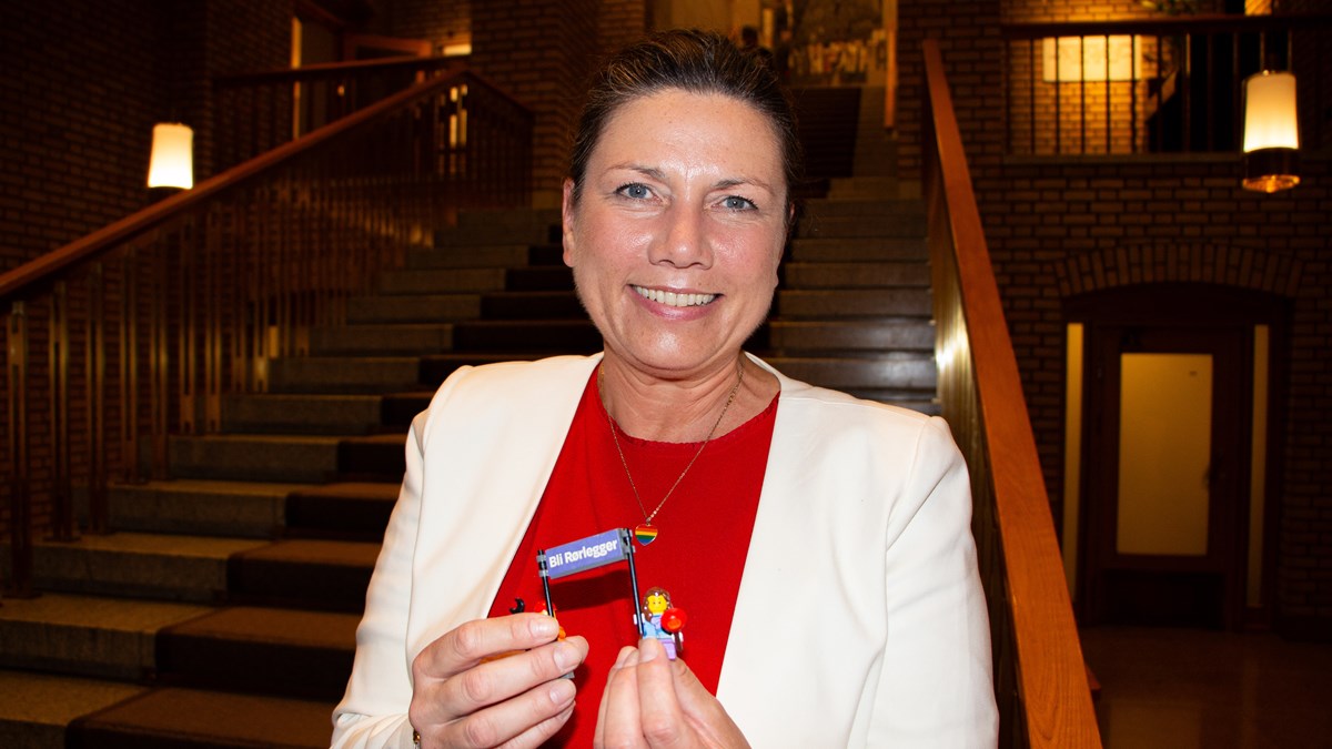 Heidi Nordby Lunde holder en rørleggerjente og rørleggergutt i lego, som ble plassert i Stortingets åpningsparti i 1. etasje.